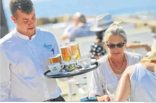  ?? JAVIER ALBIÑANA ?? Un camarero sostiene una bandeja en una terraza de Málaga.