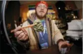  ?? DAVID ZALUBOWSKI — THE ASSOCIATED PRESS FILE ?? Matt Hart holds up a bud of Lemon Skunk, the most potent strain of marijuana available at the 3D Dispensary in Denver. A bill making its way through the Colorado legislatur­e may allow recreation­al pot growers to instantly re-classify their product as...