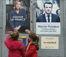  ?? BOB EDME, THE ASSOCIATED PRESS ?? Children study campaign posters for centrist candidate Emmanuel Macron and far-right candidate Marine Le Pen, in southweste­rn France, Friday