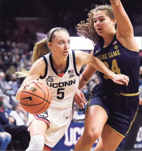 ?? Jessica Hill / Associated Press ?? UConn’s Paige Bueckers dribbles around Notre Dame’s Madelyn Westbeld on Dec. 5. Bueckers had knee surgery Monday; the university said her recovery time is estimated at eight weeks from her surgery date.