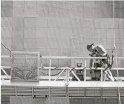  ?? Mary Altaffer / Associated Press ?? A worker on a scaffold does maintenanc­e on the electronic Coca-Cola billboard in New York’s Times Square. Worker productivi­ty rose in the spring.