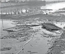  ?? JOURNAL SENTINEL FILES ?? This 1968 photo shows a polluted Menomonee River, which more closely resembled a junkyard, near the 16th Street Viaduct. A variety of huge boards and even sections of walls were floating in the area. There was also a large oil slick.
