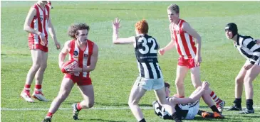  ??  ?? Trafalgar’s Corey Watts looks to evade his Yinnar opponent during the Fourths grand final, with Angus Templeton providing an option in support.