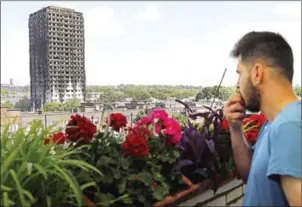  ?? TOLGA AKMEN/AFP ?? The remains of residentia­l tower block Grenfell Tower are seen from a nearby tower block, in west London, on Thursday, a day after it was gutted by fire.