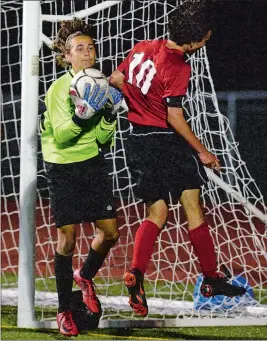  ?? DANA JENSEN/THE DAY ?? Stonington goalie Peter Fernholz makes a save as Fitch’s Caleb Robbins (10) pressures him during Wednesday’s ECC Division I boys’ soccer game. Stonington remained unbeaten with a 3-0 win. Go to theday.com to view a photo gallery.