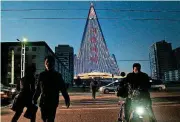  ?? [AP PHOTO] ?? People cross the street Dec. 20 as a propaganda message is displayed on the pyramid-shaped Ryugyong Hotel in Pyongyang, North Korea. For several hours each night, the building that doesn’t have electricit­y inside becomes the backdrop of a massive light show in which more than 100,000 LEDs flash images of party symbols and political slogans. North Korean leader Kim Jong Un sent a letter to South Korean President Moon Jae-in on Sunday calling for more peace talks between the leaders in the new year.