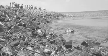  ??  ?? Emergency workers and locals stand along the shoreline of Ennore Port following a collision between two oil tankers, in Chennai. — Reuters photo