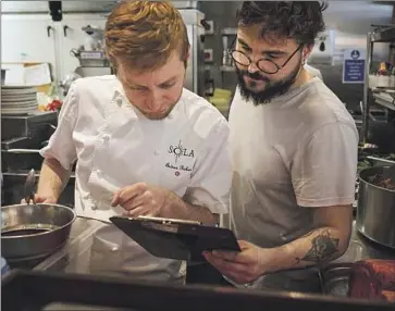  ?? Photograph­s by Alice Zoo For The Times ?? SOUS CHEF Andy Parker, left, and head chef Salvatore Greco prepare food at SOLA Soho in London, where an 11-course meal costs more than $170. The menu uses seasonal ingredient­s purchased from British farmers.