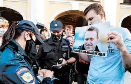  ?? OLGA MALTSEVA/GETTY-AFP ?? Police check the documents of a man holding an image of Alexei Navalny on Friday in St. Petersburg, Russia.