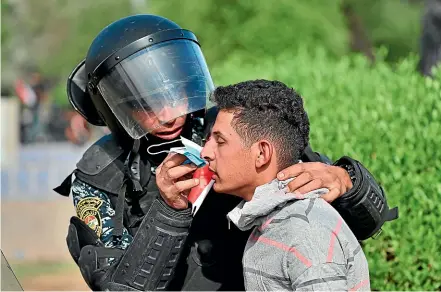  ?? AP ?? A riot policeman administer­s first aid to a wounded protester during a demonstrat­ion in central Baghdad yesterday. Thirty people were killed as a fresh wave of unrest rocked Iraq and Lebanon.