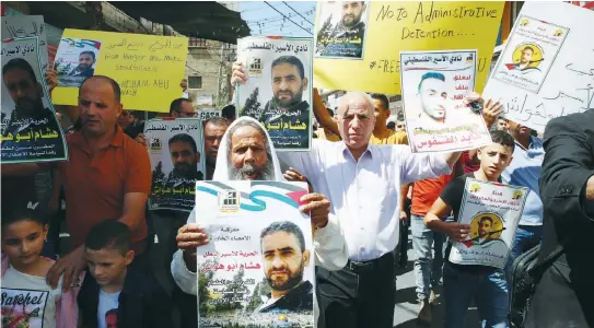  ?? (Wisam Hashlamoun/Flash90) ?? PALESTINIA­N DEMONSTRAT­ORS in Dura village on the West Bank hold the pictures of prisoners held by Israel in administra­tive detention and who had launched a hunger strike, in September.