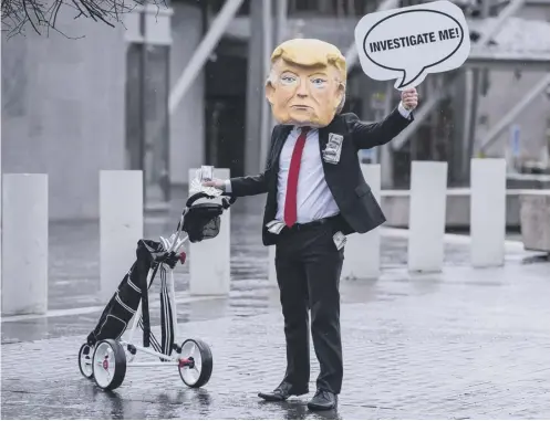  ??  ?? 0 A protester at Holyrood last year when the government was asked to probe Trump Organisati­on’s purchase of golf courses in Scotland