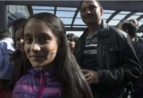  ??  ?? Krisha Brahmbhatt of Brampton shows off the Indian flag painted on her cheek as she waits in line outside the Ricoh Coliseum to see Modi.