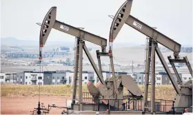  ?? MATTHEW BROWN/AP ?? Pump jacks stand with apartments in the background last month on the outskirts of Watford City, N.D., part of McKenzie County.