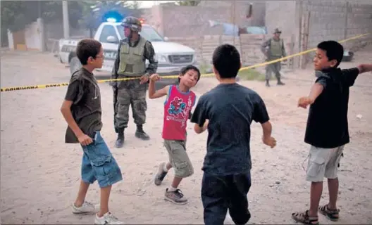  ?? SHAUL SCHWARZ / GETTY ?? Los niños mexicanos, como estos de Ciudad Juárez –junto a un cordón policial–, viven la violencia como una experienci­a cotidiana