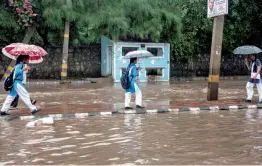  ?? — PTI ?? Schoolgirl­s walk on a road divider to protect themselves from a waterlogge­d road after heavy rains in New Delhi on Saturday.