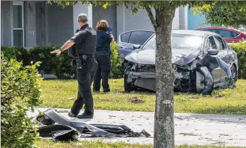  ?? PHOTOS BY LANNIS WATERS / THE PALM BEACH POST ?? Delray Beach police investigat­e the scene of a crash Monday on Southwest 10th Avenue after a shooting near Prospect Street. Police say the violence stems from a longtime feud.