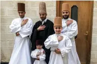  ??  ?? Sufi Dervish dancer Mahmoud Al-Kharrat (center), his brother Muayad (right behind), Muayad’s son Anas (center below) and other members of the Kharrat family pose for a picture in costume at their home in the
Shahgur district.