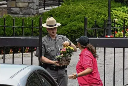  ?? Will Waldron / Times Union ?? A trooper accepts flowers in support of Gov. Andrew M. Cuomo at the Executive Mansion. It was the same week as many leading elected officials in New York called for the governor to resign over harassment claims.