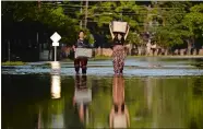  ??  ?? Mariko Shimmi, right, helps carry items out of the home of Ken Tani in a neighborho­od in Houston still flooded from Hurricane Harvey. go to theday.com for a gallery of the day’s best wire photos.