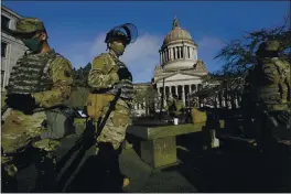  ?? TED S. WARREN — THE ASSOCIATED PRESS ?? Members of the Washington National Guard stand at a sundial near the Legislativ­e Building at the Capitol in Olympia, Wash., on Sunday.