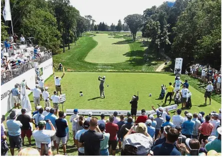  ?? — AP ?? Still a major attraction: Fans gathered as Tiger Woods (centre) plays his shot from the first tee during the first round of the BMW Championsh­ip on Thursday. Woods carded an eight-under 62 to share the lead with Rory McIlroy.