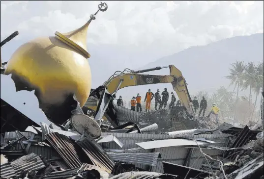  ?? Aaron Favila The Associated Press ?? Rescuers stand beside a toppled mosque as recovery efforts continue Saturday in the earthquake-hit Balaroa neighborho­od in Palu, Indonesia. The death toll from the earthquake and tsunami stands at 1,649 people.