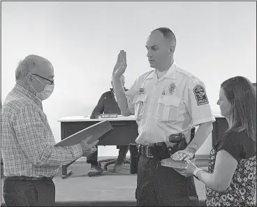  ??  ?? Pictured left: Mayor Toby Thomas swears Joe Hicks in as New London Police Chief while his wife April holds the Bible. At right: April pins the chief shield on her husband’s uniform. Photo by Lynne Phillips.