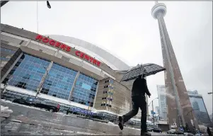  ?? CP PHOTO ?? A man walks by the Rogers Centre as reports of falling ice from the CN Tower sparked a closure of parts of the area on Toronto on Monday.