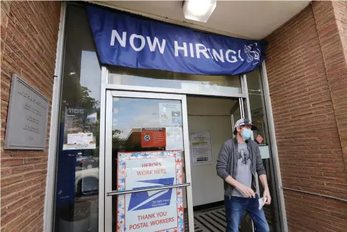  ?? AP Photo/Elaine Thompson ?? ■ A customer walks out of a U.S. Post Office branch and under a banner advertisin­g a job opening on June 4 in Seattle.