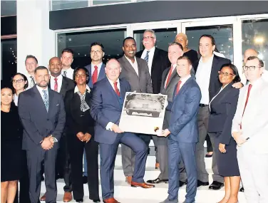  ?? CONTRIBUTE­D ?? George Wills (front row, fourth left), president & CEO, Porsche Latin America, presents Adam Stewart (front row, fifth left), CEO, ATL Automotive Group, with a plaque commemorat­ing the opening of the first Porsche Centre in Jamaica. Joining in in the...