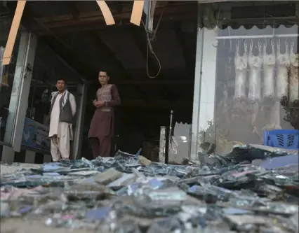  ?? Associated Press ?? Afghans stand near a damaged shop after an explosion in Kabul, Afghanista­n, earlier this month. A suicide car bomber targeted the police headquarte­rs in a minority Shiite neighborho­od in western Kabul, setting off a huge explosion that wounded dozens of people, Afghan officials said. The Taliban claimed responsibi­lity for the bombing.