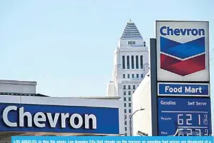  ?? —AFP ?? LOS ANGELES: In this file photo, Los Angeles City Hall stands on the horizon as gasoline fuel prices are displayed at a Chevron gas station. The US eased oil-related sanctions against Venezuela on November 26, 2022, as President Nicolas Maduro’s government and the opposition announced a humanitari­an agreement on education, health and other social issues.