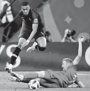  ?? Christopne Simon / AFP/Getty Images ?? French forward Kylian Mbappe jumps over a tackle attempt by Belgian midfielder Kevin De Bruyne during France’s 1-0 victory in the semifinals Tuesday.