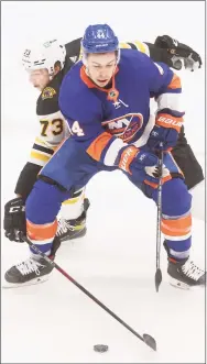  ?? Jason DeCrow / Associated Press ?? The Boston Bruins’ Charlie McAvoy (73) stretches for the puck around the New York Islanders’ Jean-Gabriel Pageau during the second period on Monday in Uniondale, N.Y.