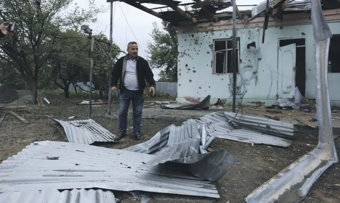 ??  ?? A man stands in a yard of a destroyed house damaged by shelling during fighting over the Armenian occupied Nagorno-Karabakh region in Aghdam, Azerbaijan, Oct. 1, 2020.
