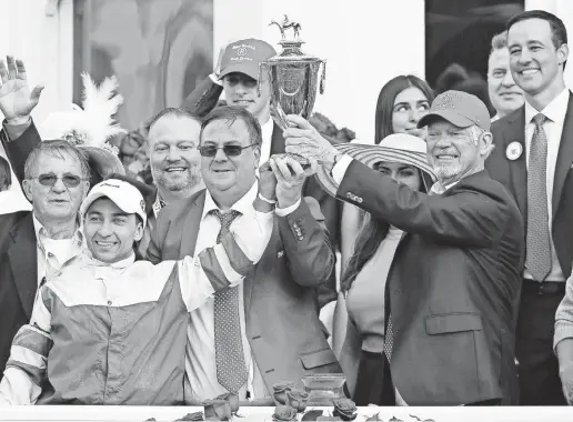  ?? SAM UPSHAW JR./THE COURIER-JOURNAL ?? Jockey Sonny Leon, trainer Eric Reed and owner Rich Dawson, right, hoisted the trophy in the winner’s circle after Rich Strike won the 148th Kentucky Derby at Churchill Downs in Louisville on May 7.