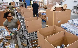  ?? STEVE SCHAEFER / FOR THE AJC ?? National Guard Pfc. Danika Martin from the 1177th Transporta­tion Company loads boxes of food supplies at the Atlanta Community Food Bank headquarte­rs last month. Gov. Brian Kemp deployed 200 members of the Georgia National Guard to support food distributi­on efforts at food banks.