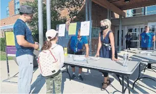  ?? CITY OF MISSISSAUG­A ?? Mississaug­a Mayor Bonnie Crombie greets a young camper from behind a plastic screen that includes posted signs about enhanced safety protocols for the city’s day camps.