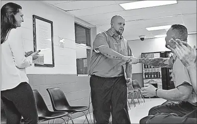  ??  ?? Ohio State senior Erin Halleran, director of the project that helps prison inmates make business plans, watches Nathaniel Ward being congratula­ted by other inmates after finishing a presentati­on about his business called the “Phoenix Project.”