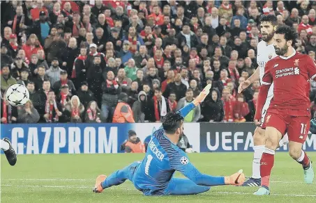  ??  ?? Mohamed Salah dinks home his second goal in Liverpool’s stunning Champions League semi-final defeat of Roma at Anfield last night.