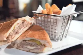  ??  ?? A Cuban sandwich is served on crisped Cuban bread alongside french fries at the Sabor Tropical restaurant.