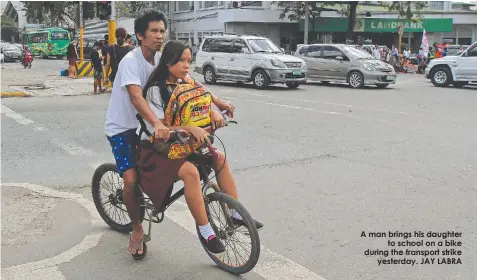  ??  ?? A man brings his daughter
to school on a bike during the transport strike
yesterday. JAY LABRA