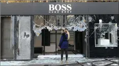  ?? HERVE BAR/AFP/GETTY IMAGES ?? A woman takes a picture of the Hugo Boss shop window that was destroyed by “Yellow Vest” demonstrat­ors on the Champs-Elysees in Paris on Saturday.