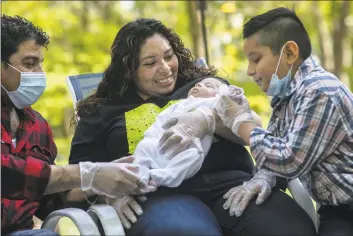  ?? John Moore / Getty Images ?? Zully, Marvin and Junior, 7, hold baby Neysel, six weeks, after they met him for the first time on Thursday in Stamford. The family, now all testing COVID-negative, brought Neysel home from Junior’s teacher Luciana Lira’s house, where she has cared for the baby since his birth.