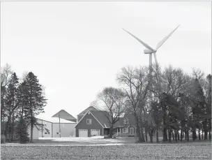  ?? CHARLIE NEIBERGALL/ASSOCIATED PRESS FILE PHOTO ?? A wind turbine stands behind a farmhouse near Northwood, Iowa, in February. A new study out of Harvard finds that ramping up wind power in America would also dial up the nation’s temperatur­es.