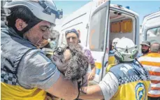  ?? FOTO: DPA ?? Täglicher Schrecken in der syrischen Provinz Idlib: Ein Weißhelm des Zivilschut­zes trägt ein verletztes Kind aus den Trümmern eines Hauses.