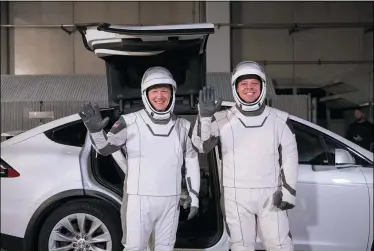  ?? KIM SHIFLETT — NASA VIA AP ?? In this Friday, Jan. 17photo made available by NASA, astronauts Doug Hurley, left, and Robert Behnken pose in front of a Tesla Model X car during a SpaceX launch dress rehearsal at Kennedy Space Center in Cape Canaveral, Fla. The NASA astronauts rode to the pad in the electric vehicle made by Elon Musk’s company.