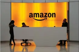  ?? AP PHOTO BY MARK LENNIHAN ?? In this Feb. 14, 2019 file photo, people stand in the lobby for Amazon offices in New York. Amazon is ending a charity donation program it ran for a decade in its latest cost-cutting move. In a blog post on Wednesday, Jan. 18, 2023, the company said the program, called Amazonsmil­e, will shut down by February 20.