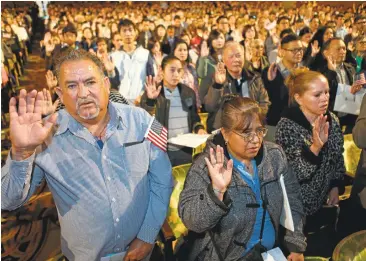  ?? ANDA CHU/STAFF PHOTOS ?? From left, Nicholas Franco, of Napa, originally from Mexico, Maria Lozano de Chacon, of Antioch, originally from Peru, and Emilia Segura, of Petaluma, originally from Mexico, take the Oath of Allegiance during a naturaliza­tion ceremony at the Paramount...